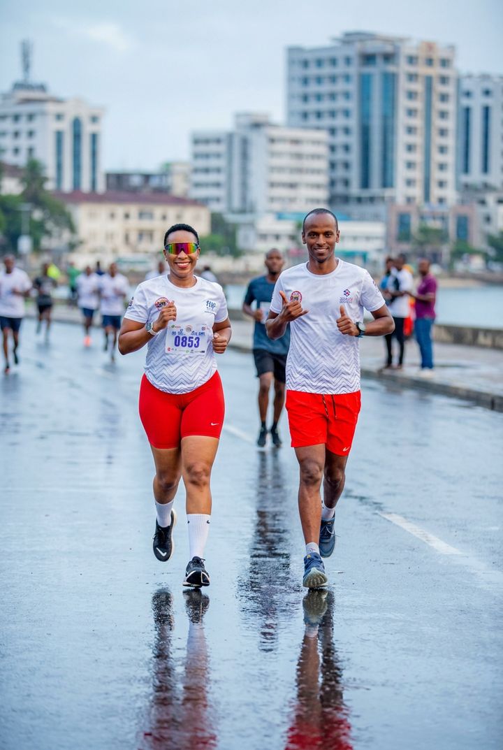 Two Runners Club members mid-stride together on a Dar es Salaam street at dawn