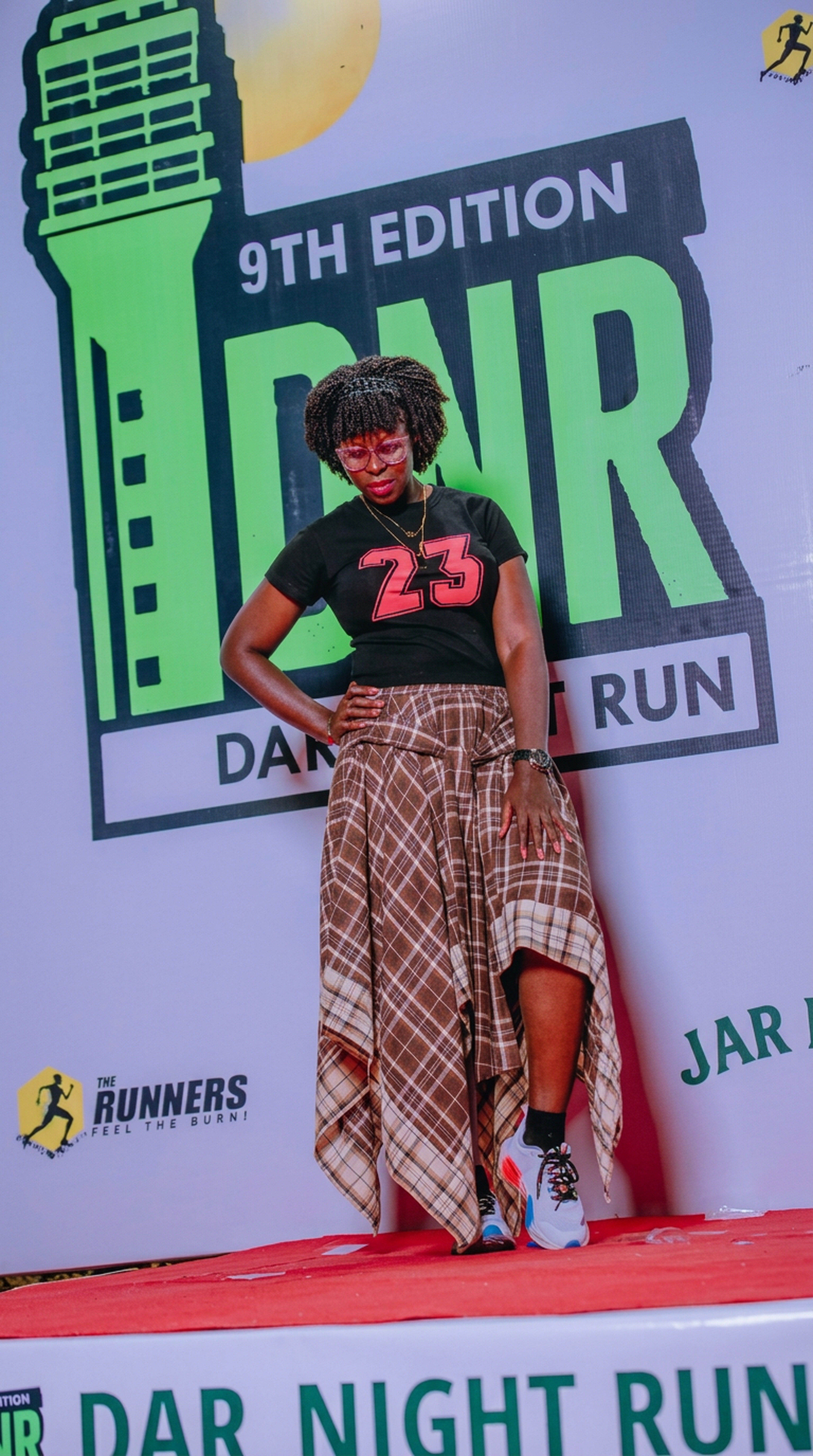Attendee in front of the Dar Night Run 9th Edition backdrop